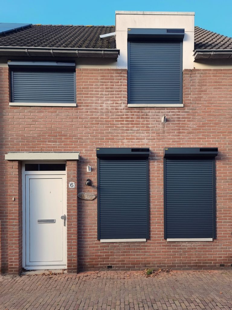 Antraciet rolluiken aan een bakstenen woning