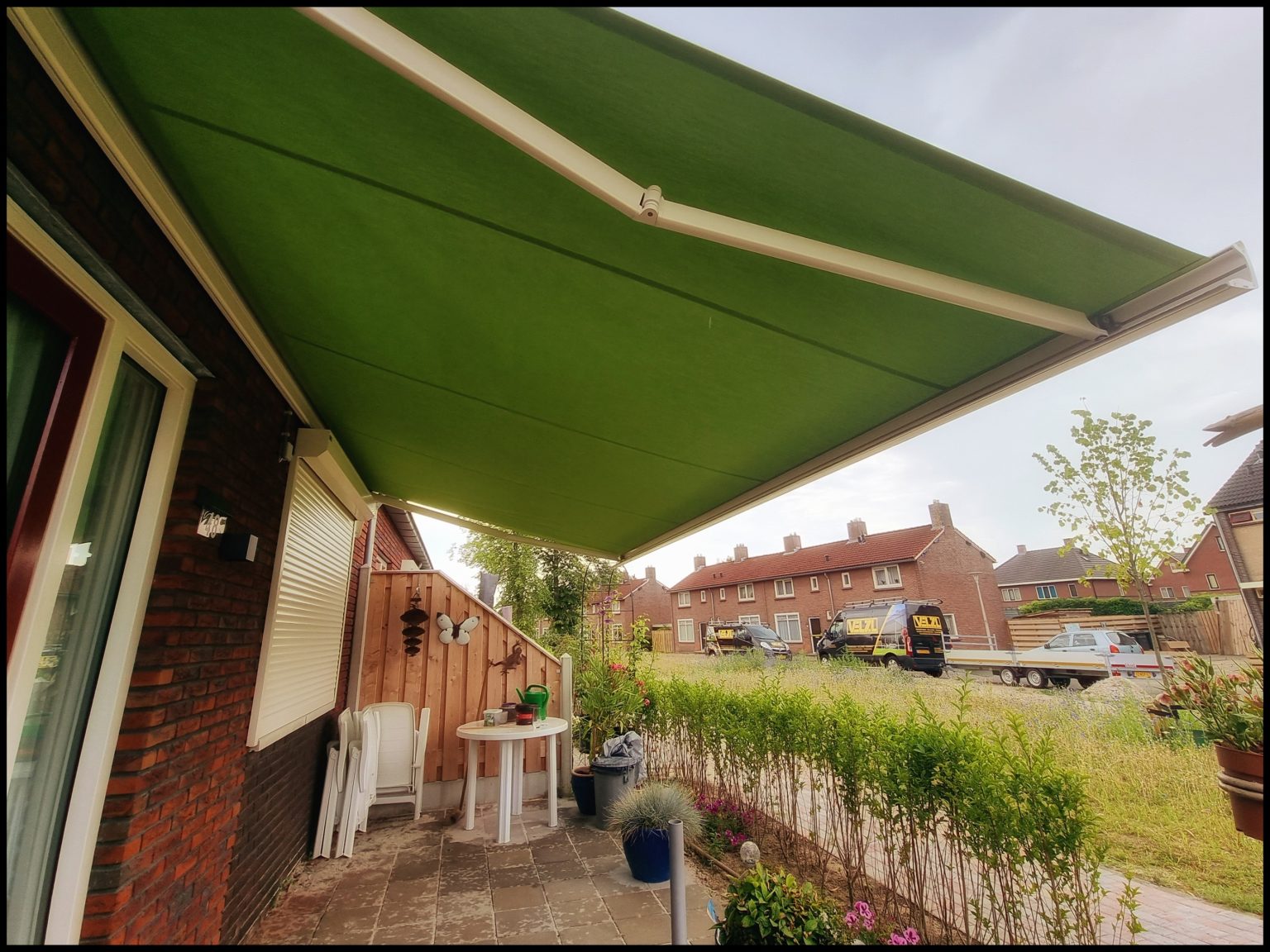 Groen knikarmscherm boven een terras