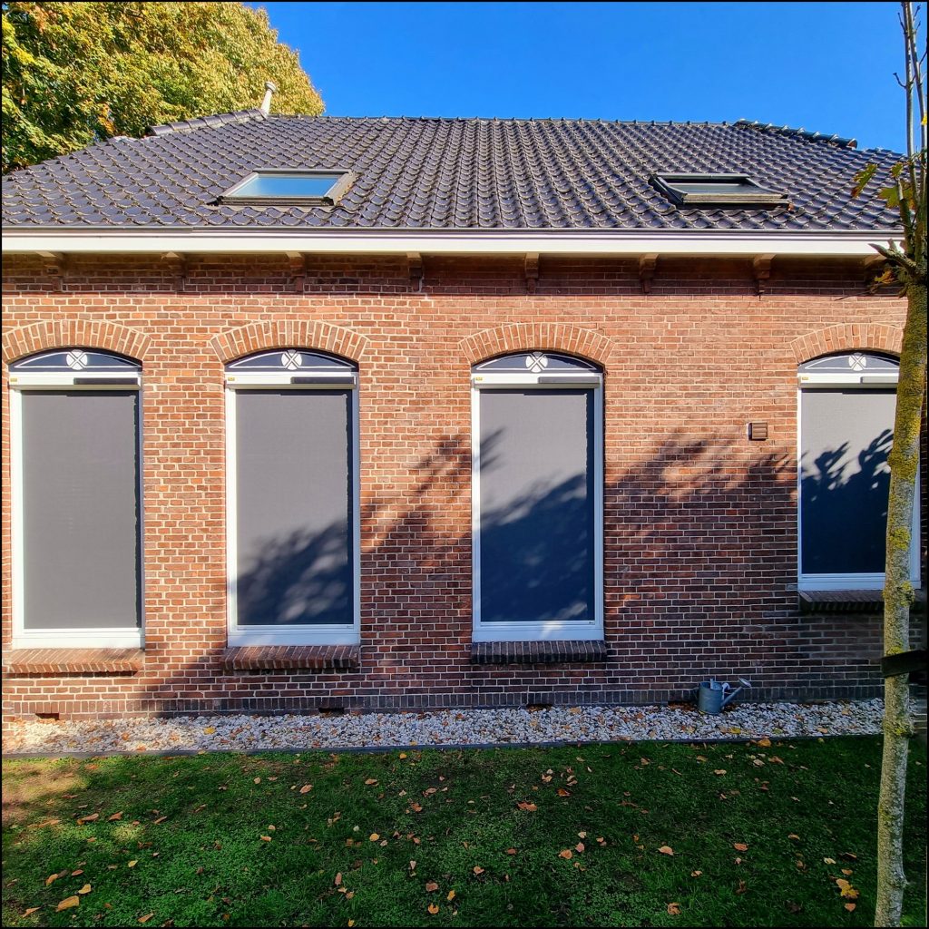 Screens aan een woning met gele gevel