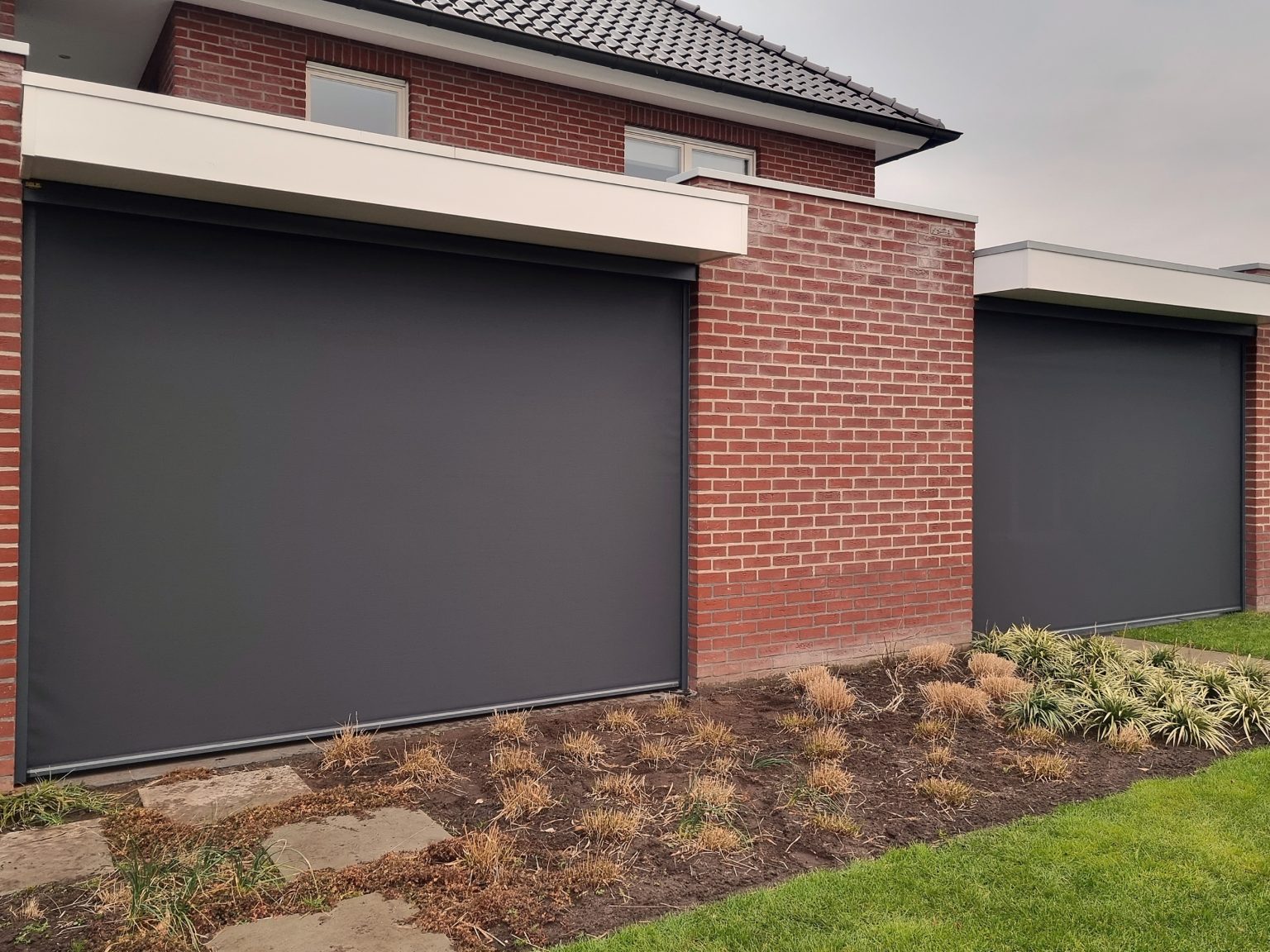 Antraciet screens aan een bakstenen woning