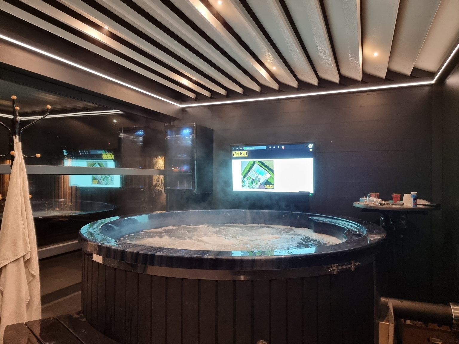 Wellnessruimte onder een lamellendak met hottub en LED-verlichting