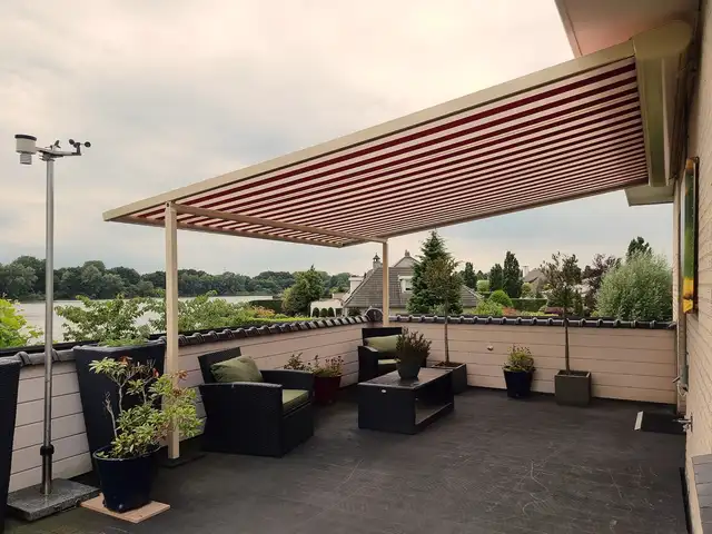 Rood-witte pergola-zonwering op een dakterras, geplaatst door VELZL