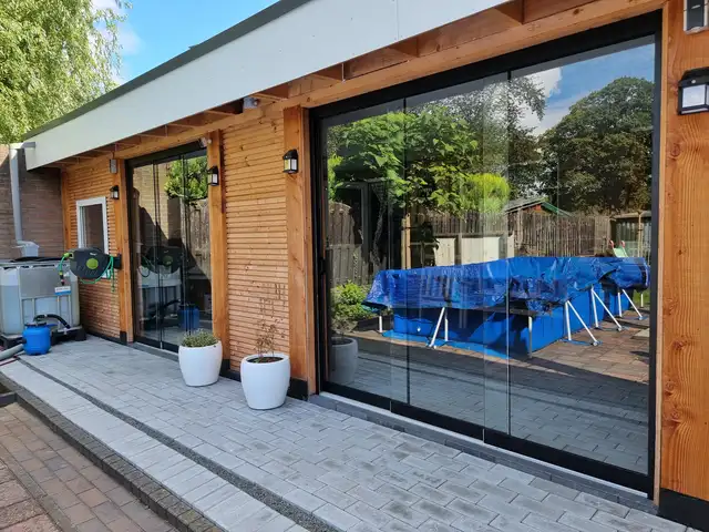 Glazen schuifwanden onder een houten overkapping, geplaatst door VELZL