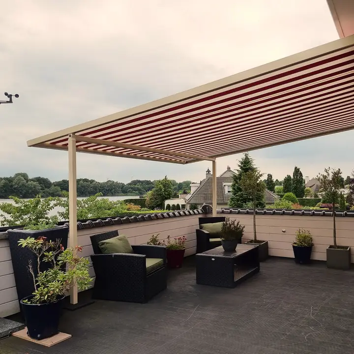 Gestreepte pergola-zonwering op staanders boven een terras aan het water