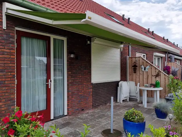 Groen knikarmscherm boven een terras, geplaatst door VELZL