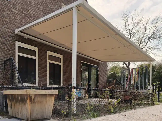 Witte pergola-zonwering aan een woning, geplaatst door VELZL